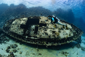 woman diver visiting an underwater wreck of a metal sailboat on a reef in the Rea Sea, Egypt