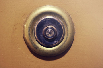 old worn metal door eye over a light brown surface - circular ring with glass