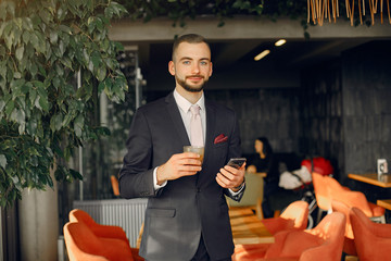 Handsome man in a black suit. Businessman working in a cafe