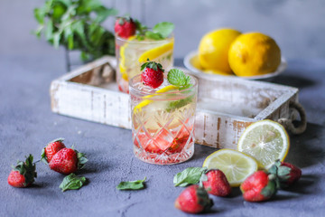 Photo of refreshing summer Strawberry infused waters. Mineral water with fresh strawberries lemon mint with a grey background. Detox water with strawberry lemon mint. Copy space. Wooden box