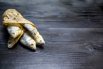 dried stockfish in a paper bag on a wooden board. Selective focus. Blur background