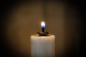 Shallow focus of a Cathedral wax candle, focusing on the bright flame. A candle collar is seen...