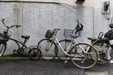 Old bicycles against a house exterior wall.