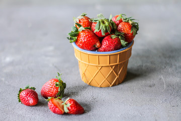 Photo of heap of fresh strawberries in the bowl on rustic grey background..A bunch of ripe strawberries in a bowl on the table. Copy space. Healthy fresh fruit. Organic food. Clear food
