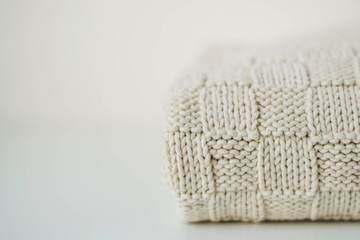 Knitted texture. Beige plaid on a white table on the right. Copy space on the left side.