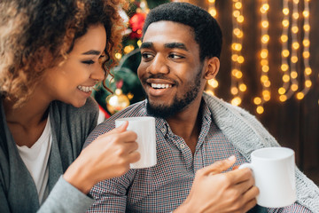 Young couple drinking coffee at Christmas tree