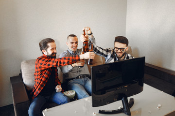Fans sitting on the couch in the living room. Guys drinking a beer