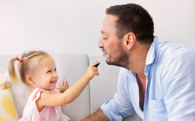 Little daughter doing makeup to her daddy