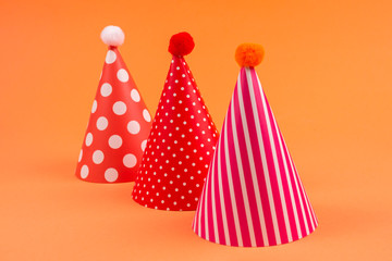 Colorful birthday caps on orange background.