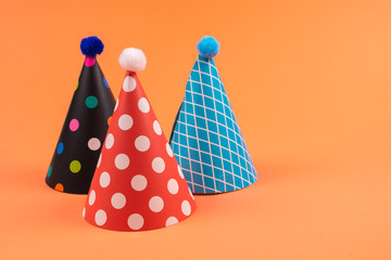 Colorful birthday caps on orange background.