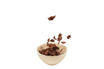Chocolate corn flakes falling to the white bowl isolated on white. Motion.