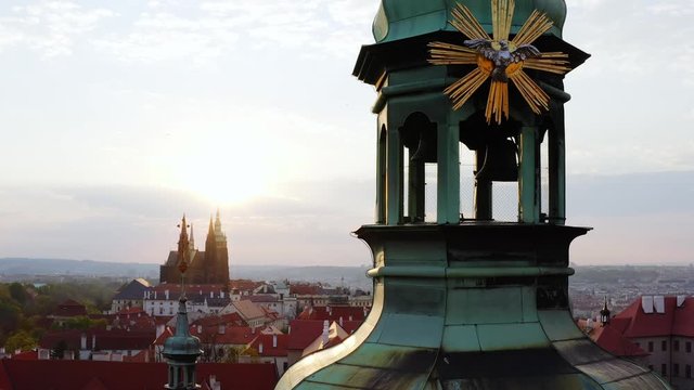 Cropped view belfry cathedral at sunrise. Lateral movement, sun shining through cathedral tower while drone moving near building decorated symbol of christianity, Aerial panorama above Prague 