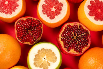 Fototapeta na wymiar Grapefruit, orange, pomegranate, citrus sweetie on red background.