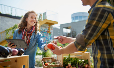 Friendly woman tending an organic vegetable stall at a farmer's - 305755802