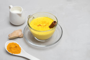 Healthy ayurvedic drink turmeric golden milk with turmeric powder, ginger root, milk and cinnamon stick