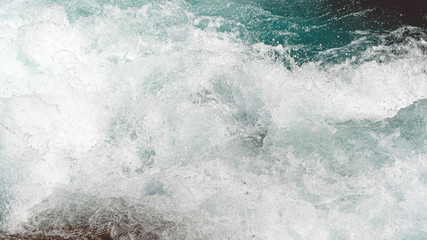 Turquoise water in river with stone shore. Sea tide, seething blue water in mountain stream