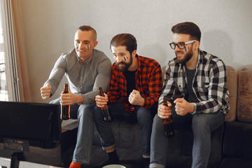 Fans sitting on the couch in the living room. Guys drinking a beer