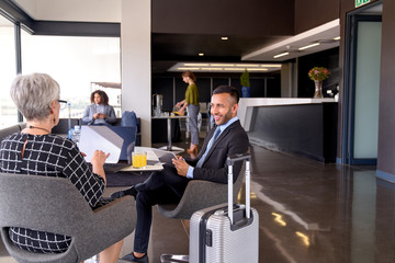 Diverse business partners sitting in modern airport lounge with - 305757684