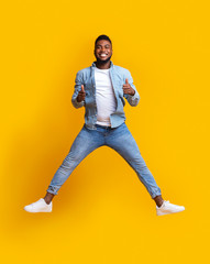 Happy african man jumping in air with his thumbs up