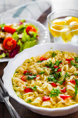 instant noodles in white bowl on wooden table background and vegetables salad on plate