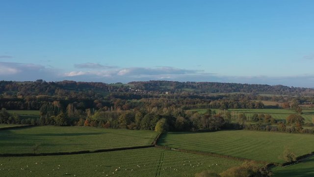 Wide aerial dolly shot of Bourton-On-The-Hill in the Cotswolds, UK. Beautiful autumnal scene with a push into the village.