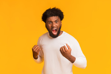 Furious afro guy shouting over orange background