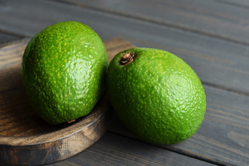 Whole fresh avocado in wooden rustic plate on wooden table background - Image