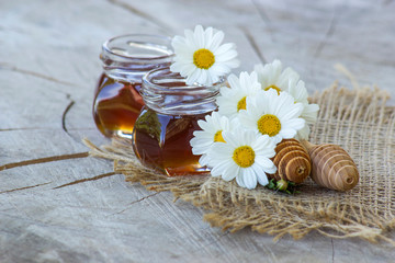 honey and flowers on wooden background