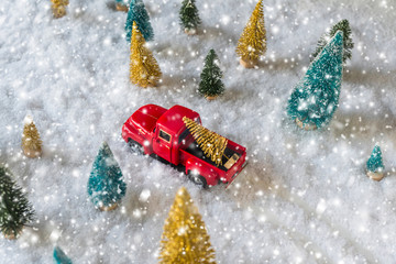 Creative Christmas decoration with red truck and colorful snowy spruces in the snow. Winter forest. Aerial, top view. Flat lay