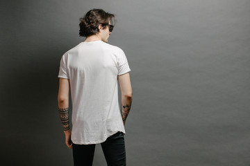 Hipster handsome male model with glasses wearing white blank t-shirt and black jeans with space for...
