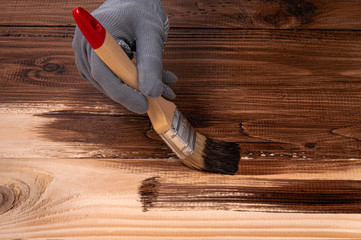 The girl paints with brown paint. Girl with a brush in her hand paints wooden boards. DIY photophone.