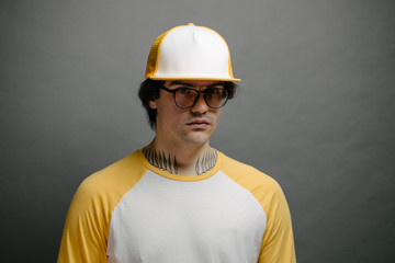 Hipster handsome male model wearing yellow blank baseball cap with space for your logo over gray background
