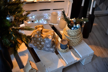 Christmas present tied with a beige ribbon and lies under the Christmas tree. A bright photo in light shades was taken on a bright day.