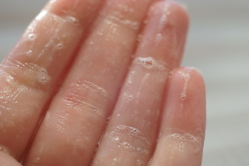 Wet fingers with soap foam, macro photo.