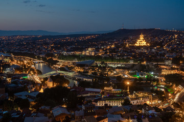 Fototapeta na wymiar Night view of Tbilisi with Sameba (Trinity) Church and other landmarks. Beautiful Place to travel.
