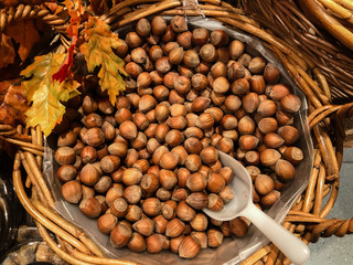 A basket of brown hazelnuts with white  scoop on farmer market.