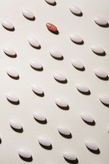 White pills linen pattern on white background. One red is different. Healthcare and medical concept.