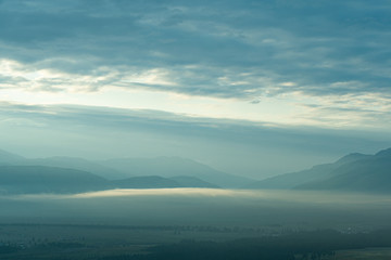 Gentle hills in bluish haze. Soft light in early morning, silhouettes of mountains