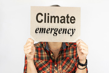 Conceptual photo of a woman on a light background with a tablet in her hands with the words Climate Emergency