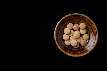 Maca (Lepidium meyenii, known as Peruvian ginseng). Concept for a healthy dietary supplementation. Black paper background. Top view. Close up.