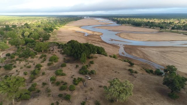 Aerial view of a 4x4 safari vehicle driving along the side of a river in Gonarezhou National Park, Zimbabwe