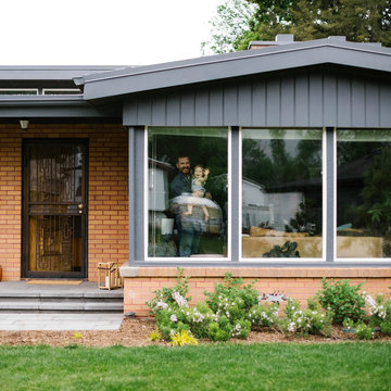 Father holding his daughter behind window of house