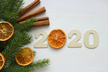 Christmas holiday background. Figures 2020 on a white wooden background, dried orange slices, spruce branches. Copy space. New year 2020 concept, Christmas card.
