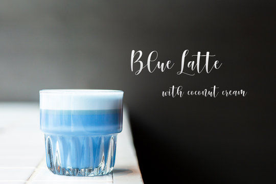 Blue latte with coconut cream white tile on a black background. Blue match latte in a glass isolated on white background, clipping path included. The inscription with the name of the drink. Hot coffee