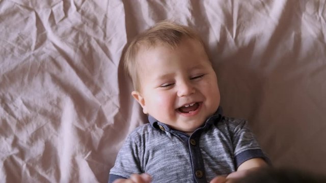 Top view of baby looking at camera and smiling, close up sloe motion. A cute little baby is look and smile. Babyboy looks around and smiles and laughs, view drom above