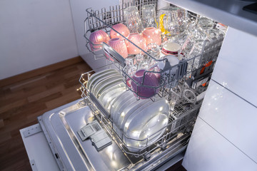 Dishwasher with dishes in kitchen furniture.