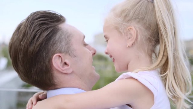 Middle-aged father embraces his 5 years blonde daughter. Fair-haired little 5 years old girl smiles happily