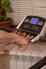 Hands of an old 85 year old woman. Close-up. A woman is engaged at home on a treadmill. Active old age.