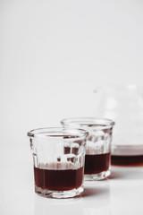 Transparent glass teapot and glasses with tea or coffee on white background