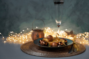 Christmas table setting. Golden decoration with gift box, glass baubles and defocused lights. Christmas and New Year holidays concept. Flat   lay.Front view